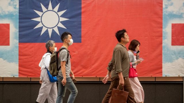 台北街头路人走过一面印上青天白日满地红旗的横幅（6/4/2023）
